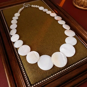 Bohemian geometric shell necklace with white mother-of-pearl discs on a vintage background