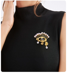 Detail of Eye of Horus brooch with gold metal and pearls on a black sweater