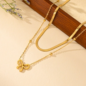 Elegant gold double-layered butterfly necklace with snake chain on a textured backdrop