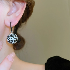 Vue détaillée des boucles d'oreilles léopard portées par un mannequin pour un look chic