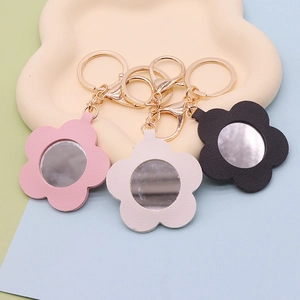 Close-up of floral PU leather keychain mirrors in pink and black on cloud tray