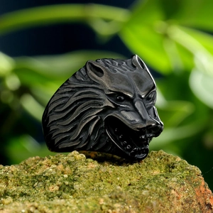 Macro shot of retro titanium steel wolf head ring with vintage texture on mossy rock