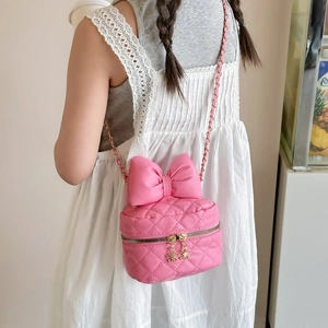 Pink bow quilted crossbody bag with golden chain strap on model in white lace dress