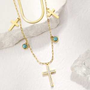 Detail of gold double-layer necklace with turquoise, crystal cross, and snake chain