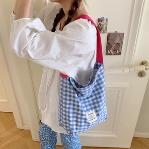 Sac fourre-tout en toile à carreaux bleus et blancs avec bandoulière rose porté par un modèle