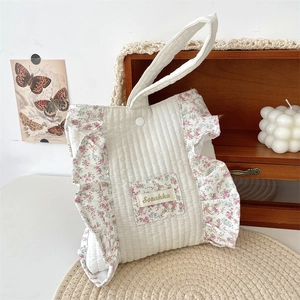 Detail of quilted cotton floral handbag featuring ruffled edges and vintage logo patch