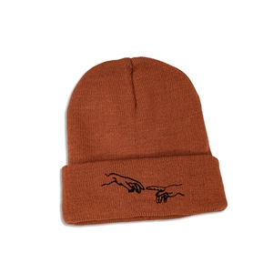 Détail du bonnet en maille orange rouille avec broderie main unique sur le revers