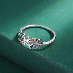 Macro shot of silver olive branch ring with colorful zircon stones on green base