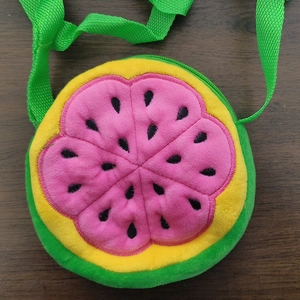 Detail view of a plush round watermelon slice crossbody bag for kids with pink inner pulp