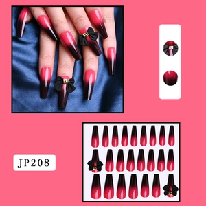 Detail of JP208 red black gradient press-on nails with black bow and gold accents