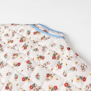 Detailed close-up of floral quilted cotton fabric with blue contrast binding trim
