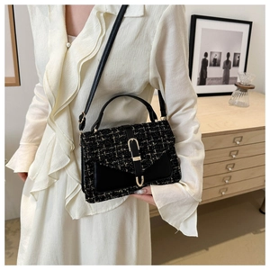 Detail of tweed crossbody bag with gold buckle on a white dress model in cozy room