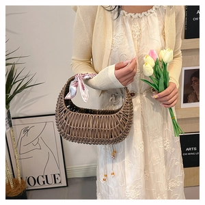 Brown half-moon rattan handbag featuring a pink patterned scarf tied on the handle