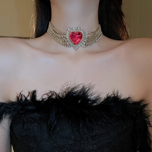 Close-up of golden choker with five rows of diamonds and a red heart pendant