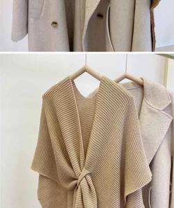 Close-up of oatmeal knitted shawl featuring a unique front knot design and textured fabric