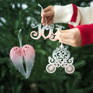 Pink gradient Christmas tree ornaments with JOY letters and wings on a green tree
