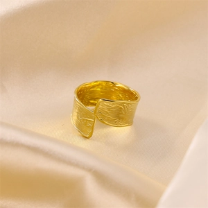 Wide gold punk style open ring with hammered metal texture on silk fabric