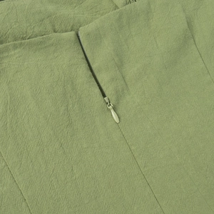 Close-up of grass green cotton dress fabric texture with hidden zipper closure detail