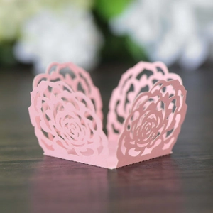 Macro shot of pink laser-cut paper candy tray with intricate rose pattern details