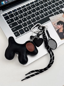 Detail of leather dog keychain with heart charm and mini tennis racket on a laptop