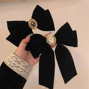 Detailed macro view of black velvet bow hair clips with vintage pearl and rose ornaments
