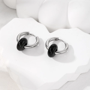 Macro detail of silver stainless steel hoop earring with a polished black natural stone bead