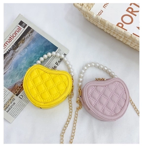Detail of heart-shaped quilted bags with white pearl handles and gold chain straps