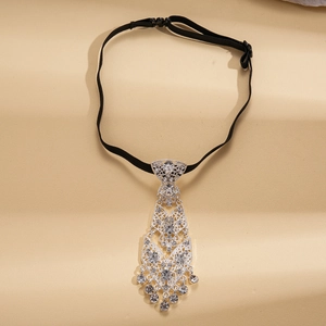 Detailed view of silver rhinestone tie necklace with tassels on champagne background