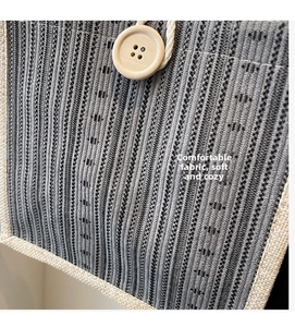 Detail of linen tote bag featuring striped fabric, rustic hemp trim, and wooden button