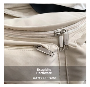 Detailed close-up of smooth metal zippers and fabric texture on a cream crossbody bag