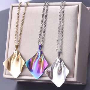 Detailed close-up of three irregular pleated metal pendants in gold, silver and iridescent