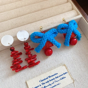 Detail view of retro earrings with resin beads and blue woven bow in a jewelry box