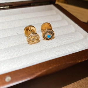 Detail von 18K vergoldeten Sonnen- und Evil-Eye-Ohrsteckern mit Zirkonia in Schmuckbox