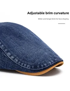 Detail of the washed denim flat cap showing wide curved brim and double stitching