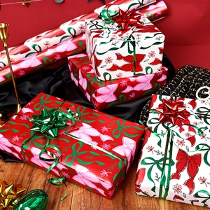 Pink and green Christmas wrapping paper rolls with decorative bows and metallic ribbons