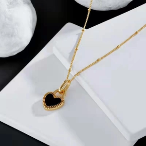 Close-up of golden necklace featuring a black heart pendant with radial edge textures