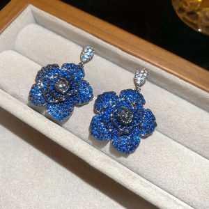 Macro shot of dark blue zircon camellia flower earrings with sparkling pavé details