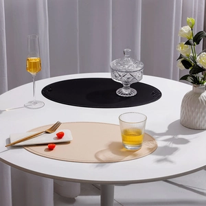 Detail of oval faux leather placemats in black and beige on a dining table setup