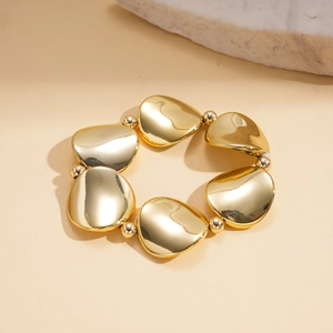Detail of high-polished gold metal bracelet with irregular pebble shapes and small beads