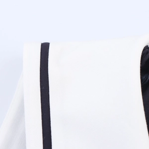 Detailed close-up showing white fabric with black contrast trim and fine stitching