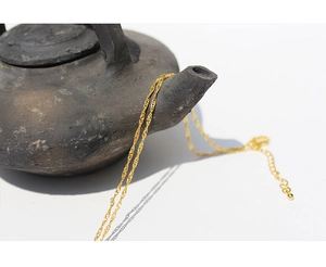 Detail of delicate gold water-wave chain with adjustable extender on a vintage teapot