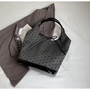Detail of grey bucket bag with black ribbon bow, textured fabric and glossy leather