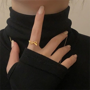 Close-up of a delicate golden bow ring worn on a finger, minimalist elegant jewelry