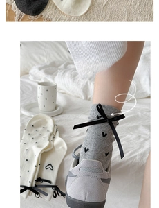 Close-up of gray knit mid-calf socks with black heart patterns and silk ribbon bows