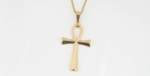Detailed close-up of golden Ankh cross necklace on white background with sharp metal texture