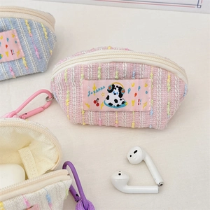 Detail view of woven cream earphone pouches with cartoon patches and colorful carabiners