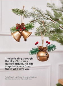 Close-up of golden Christmas bells with pine needles, cones and berries on snowy branch