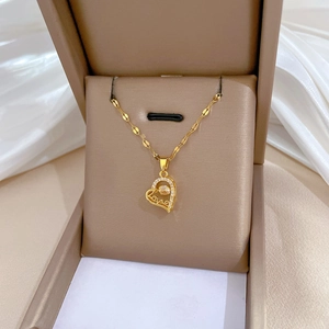 Detail of gold heart pendant with Love engraving and zircon in a jewelry box