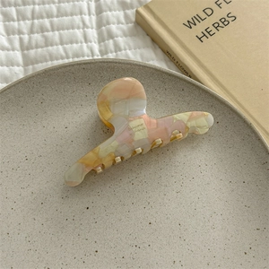 Detail view of a French acetate hair claw with mosaic pattern on a ceramic plate