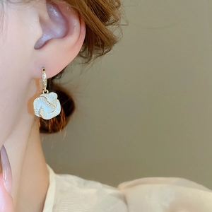 Close-up of elegant flower earrings with white petals and gold-plated zircon ear hooks